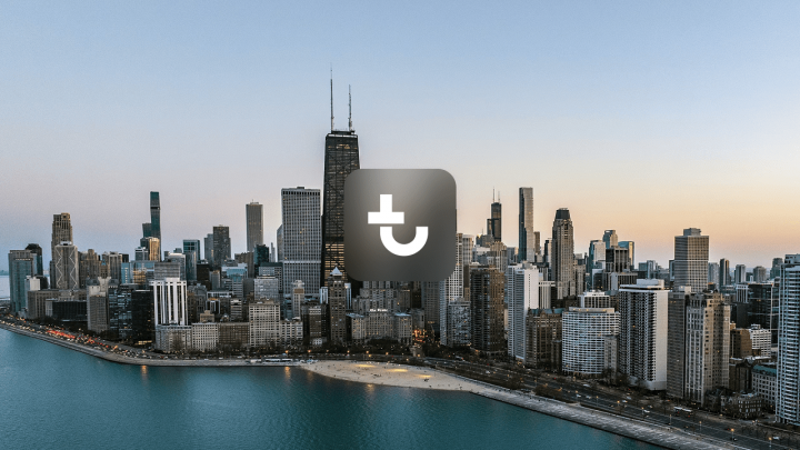 Aerial view of Chicago’s skyline at dusk with a dark square icon centered, highlighting the city for Downtime Summit.