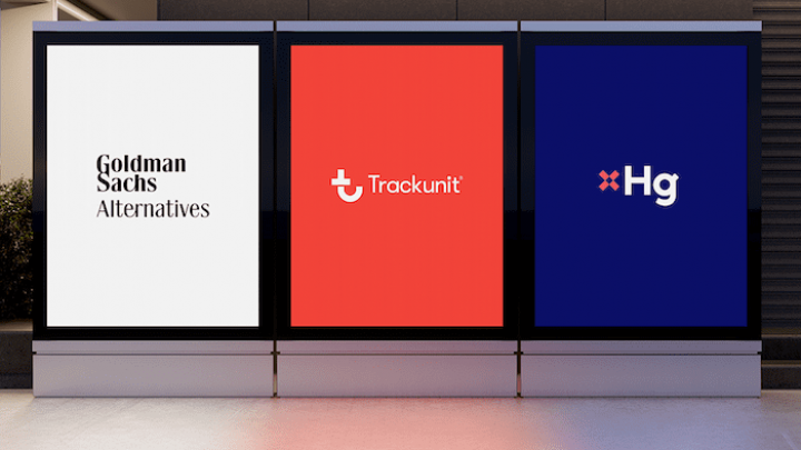 Three illuminated billboards show Goldman Sachs Alternatives, Trackunit, and Hg logos outdoors at night.