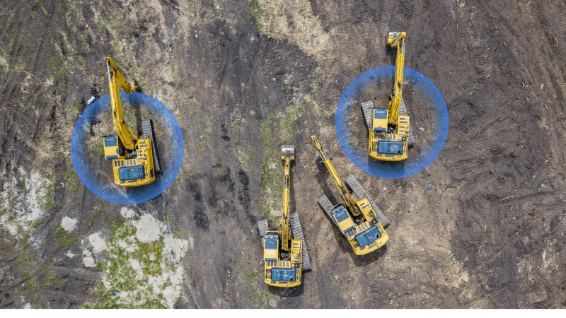 Aerial view of four yellow excavators on a construction site with two highlighted, illustrating equipment tracking for fleet management.
