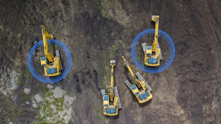 Aerial view of three yellow excavators on dirt with blue overlays showing operating ranges, illustrating construction equipment tracking.