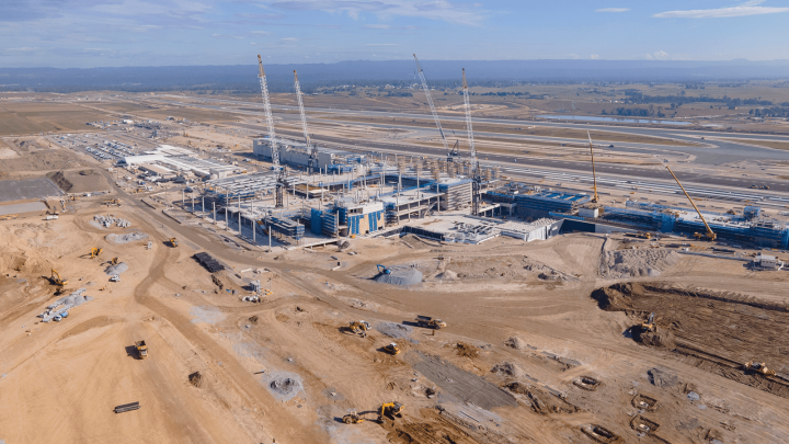 Aerial view of a large construction site with cranes, equipment, and vehicles arranged for efficiency, highlighting fleet management.
