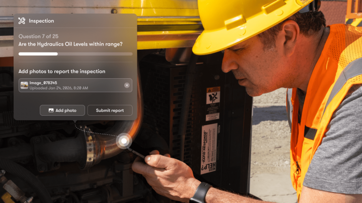 A man in a hard hat inspects outdoor machinery with a flashlight, next to a digital checklist for construction equipment tracking.