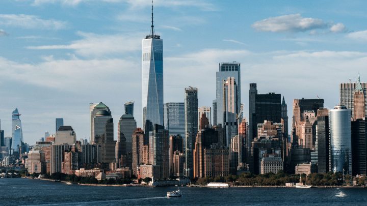 New York City skyline with One World Trade Center, skyscrapers, and a boat on the Hudson River—a calm scene for a Downtime Summit.