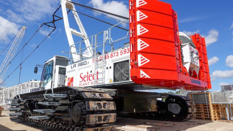 A white and red crawler crane with heavy-duty tracks and “Select Plant” branding is parked on a jobsite, showcasing fleet management.