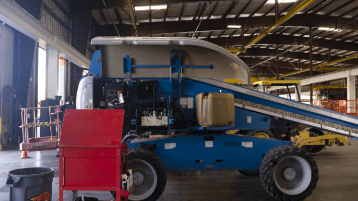 A blue and white industrial machine with a conveyor belt sits in a warehouse among tools, equipment, and fleet vehicles for fleet management.