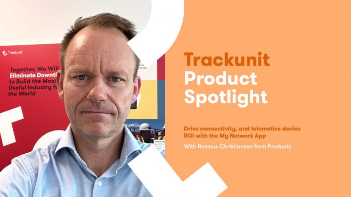 Man with short hair and a blue shirt stands by colorful posters about Trackunit’s My Network App for telematics in construction.