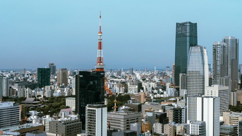 Tokyo cityscape with high-rises and Tokyo Tower under a clear sky, overlooking a tranquil Downtime Summit; connected jobsite theme.
