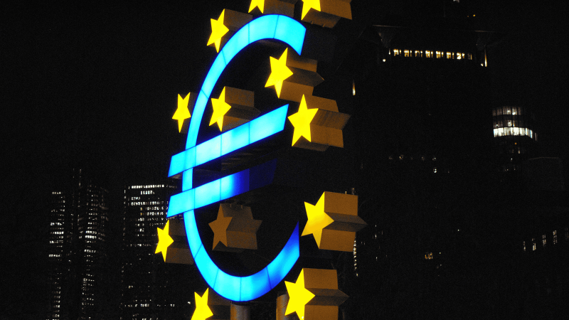 Large illuminated euro symbol with yellow stars stands outdoors at night, tall buildings and city lights in the background hinting at EU funding for construction and connected jobsite growth in Central and Eastern Europe.