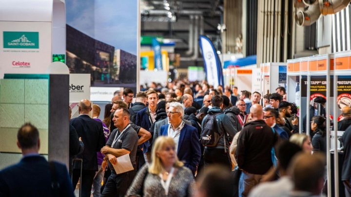 Crowds walk through a busy UK Construction Week 2026 exhibition hall, visiting booths focused on construction and connected jobsites.
