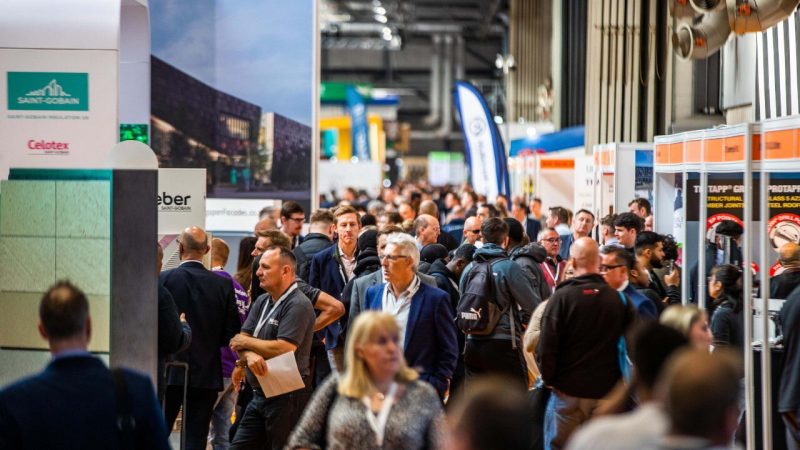 Crowds walk through a busy UK Construction Week 2026 exhibition hall, visiting booths focused on construction and connected jobsites.