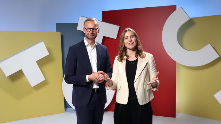 A man in a navy suit and woman in a cream blazer smile together by colorful geometric panels, reflecting inclusion and connected jobsite.