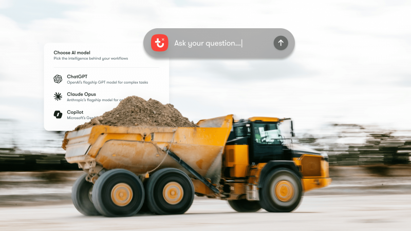 A yellow dump truck filled with dirt drives across a construction site; UI for AI models and Trackunit IrisX MCP construction IoT integration.