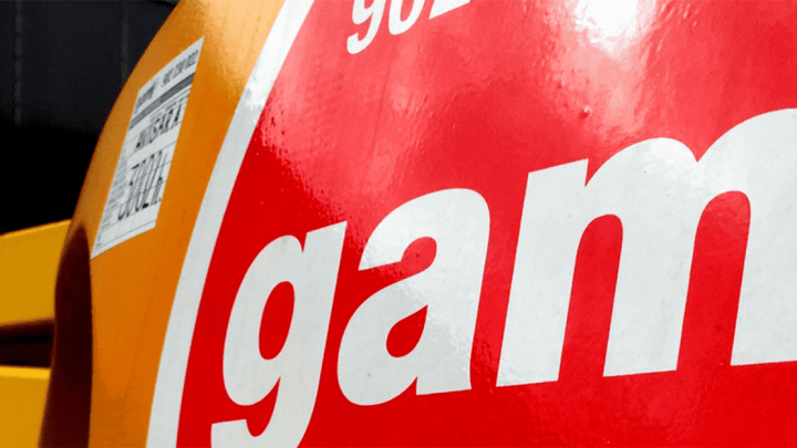 Close-up of a red circular sign with white text "gam," orange background, yellow bar, and label—linked to construction equipment tracking.