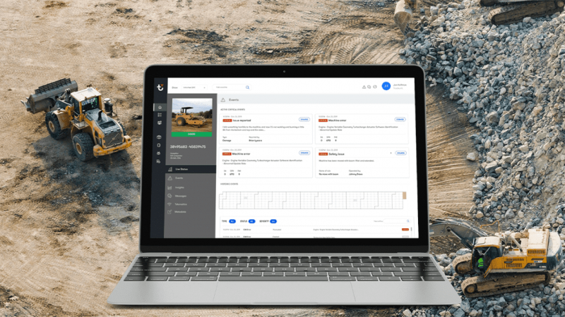 A laptop with a construction management dashboard is overlaid on a site where bulldozers work, highlighting connected jobsite.