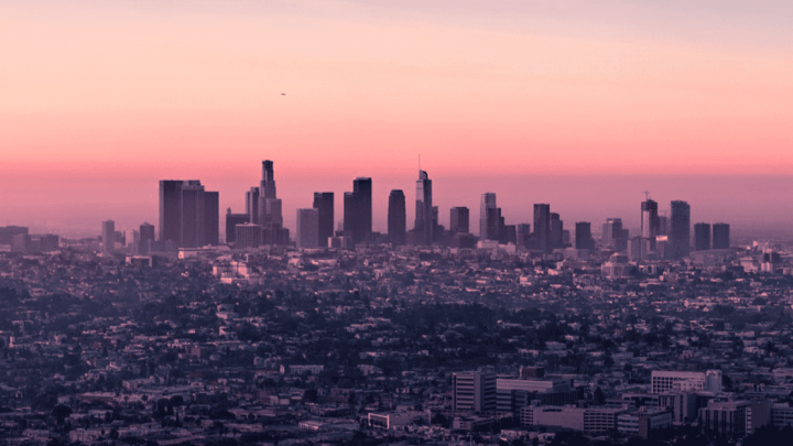 A city skyline with high-rises under construction is silhouetted at sunset, highlighting the connected jobsite in the urban foreground.