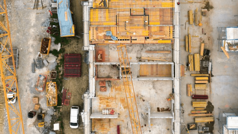 Aerial view of a construction site with scaffolding, building materials, cranes, and equipment—showcasing a connected jobsite.