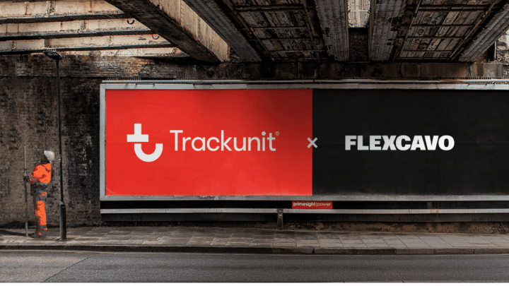 A worker in orange gear stands by a wall under a bridge, next to a billboard with Flexcavo and Trackunit logos on red and black.