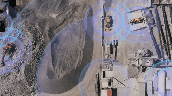 Aerial view of a construction site with Trackunit-equipped machinery, blue circles highlight equipment connectivity for fleet management.