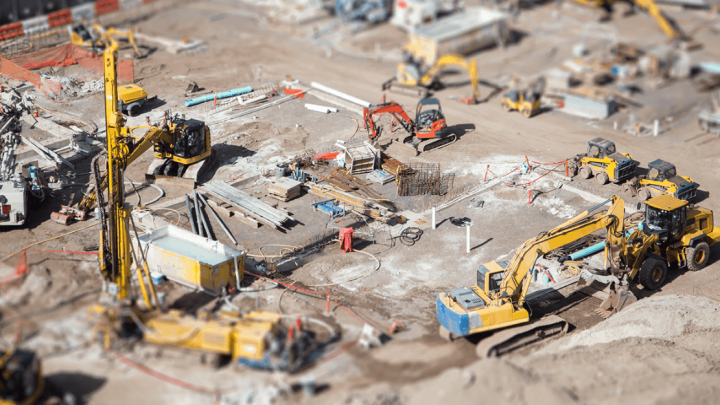 Aerial view of a busy construction site with yellow equipment and workers collaborating, illustrating a connected jobsite.