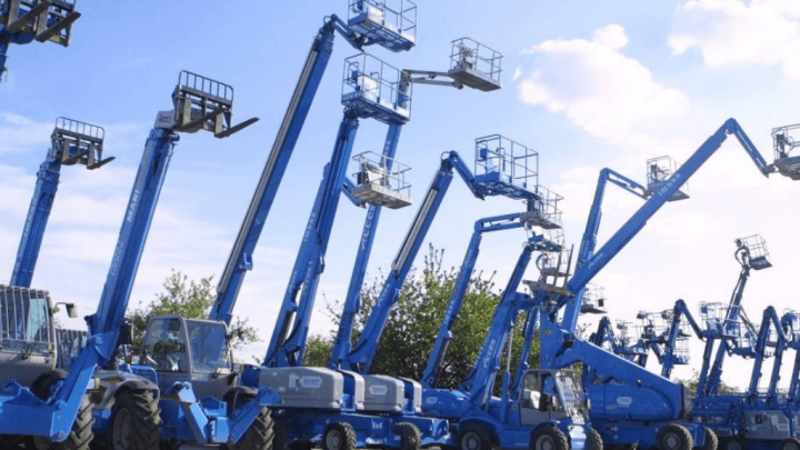Blue boom lifts and cherry pickers are lined up outdoors under a cloudy sky, highlighting a fleet management scene.
