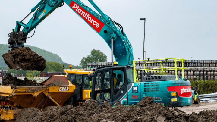A blue Plantforce excavator loads soil into a yellow dump truck at a muddy site, highlighting construction equipment tracking.
