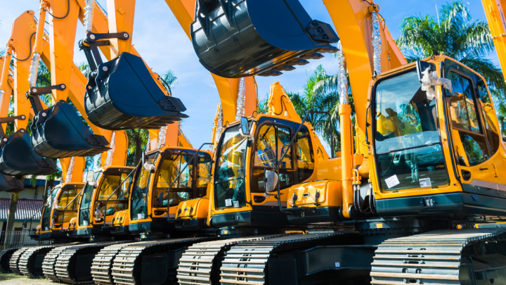 A row of yellow excavators with telematics systems stand outdoors under a sunny sky, highlighting connected jobsite equipment.