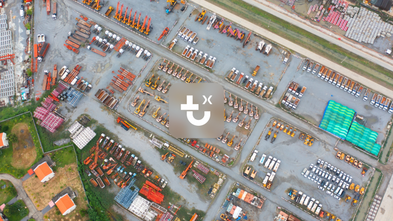 Aerial view of an IrisX yard with parked trucks, excavators, and construction materials for fleet management.