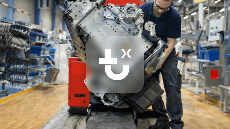 A worker uses a red IrisX machine to move an engine block in a factory, highlighting construction IoT on the busy shop floor.